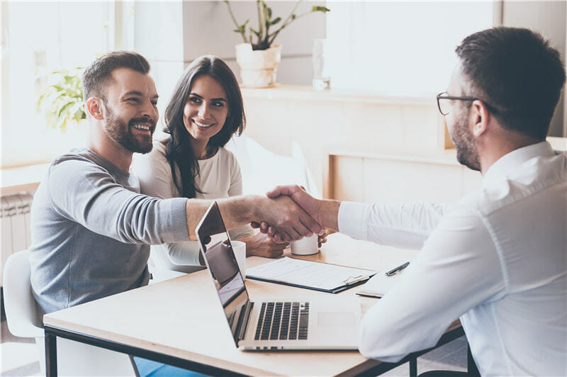 Couple handshaking with man